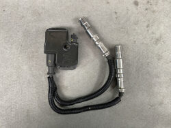 Automotive sensor module with two flexible metal hoses and connectors resting on a gray surface (likely part of a hydraulic or fuel system). Mercedes-Benz W202 W203 Genuine IGNITION COIL Pack / A0001587803 / M112, M113 Engine #1 #2 » JDM-PARTS NZ