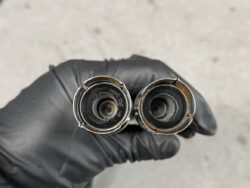 Two small camera lens barrels with glass fronts, held by a gloved hand.