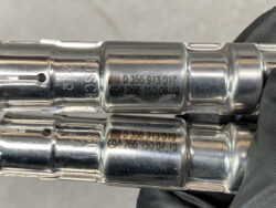 Two Bosch metal engine components with stamped part numbers (e.g., 0 356 913 017) visible on the surface, photographed in close-up.