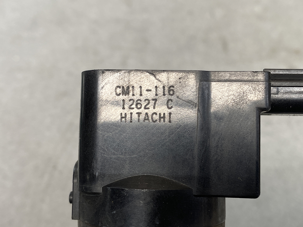 HON-COIL-CM11-116_2 HONDA Genuine IGNITION COIL CM11-116 / L-series Engine » NZ.95 » JDM-PARTS NZ » JDM-PARTS NZ Close-up of a black plastic component with stamped model text 'CM11-16 12627 C HITACHI'. HONDA Genuine IGNITION COIL CM11-116 / L-series Engine » JDM-PARTS NZ
