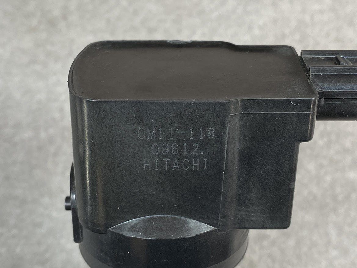 HON-COIL-CM11-118_2 HONDA Genuine IGNITION COIL CM11-118 / L-series Engine » NZ.95 » JDM-PARTS NZ » JDM-PARTS NZ Close-up of a black plastic component marked 'CM1-118', '09612', Hitachi, with a circular mounting base underneath. HONDA Genuine IGNITION COIL CM11-118 / L-series Engine » JDM-PARTS NZ