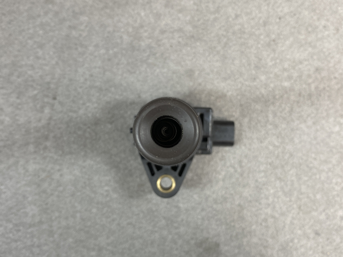 HON-COIL-CM11-118_5 HONDA Genuine IGNITION COIL CM11-118 / L-series Engine » NZ.95 » JDM-PARTS NZ » JDM-PARTS NZ Automotive camera module with a circular lens in a black plastic housing mounted on a small bracket on a gray surface HONDA Genuine IGNITION COIL CM11-118 / L-series Engine » JDM-PARTS NZ