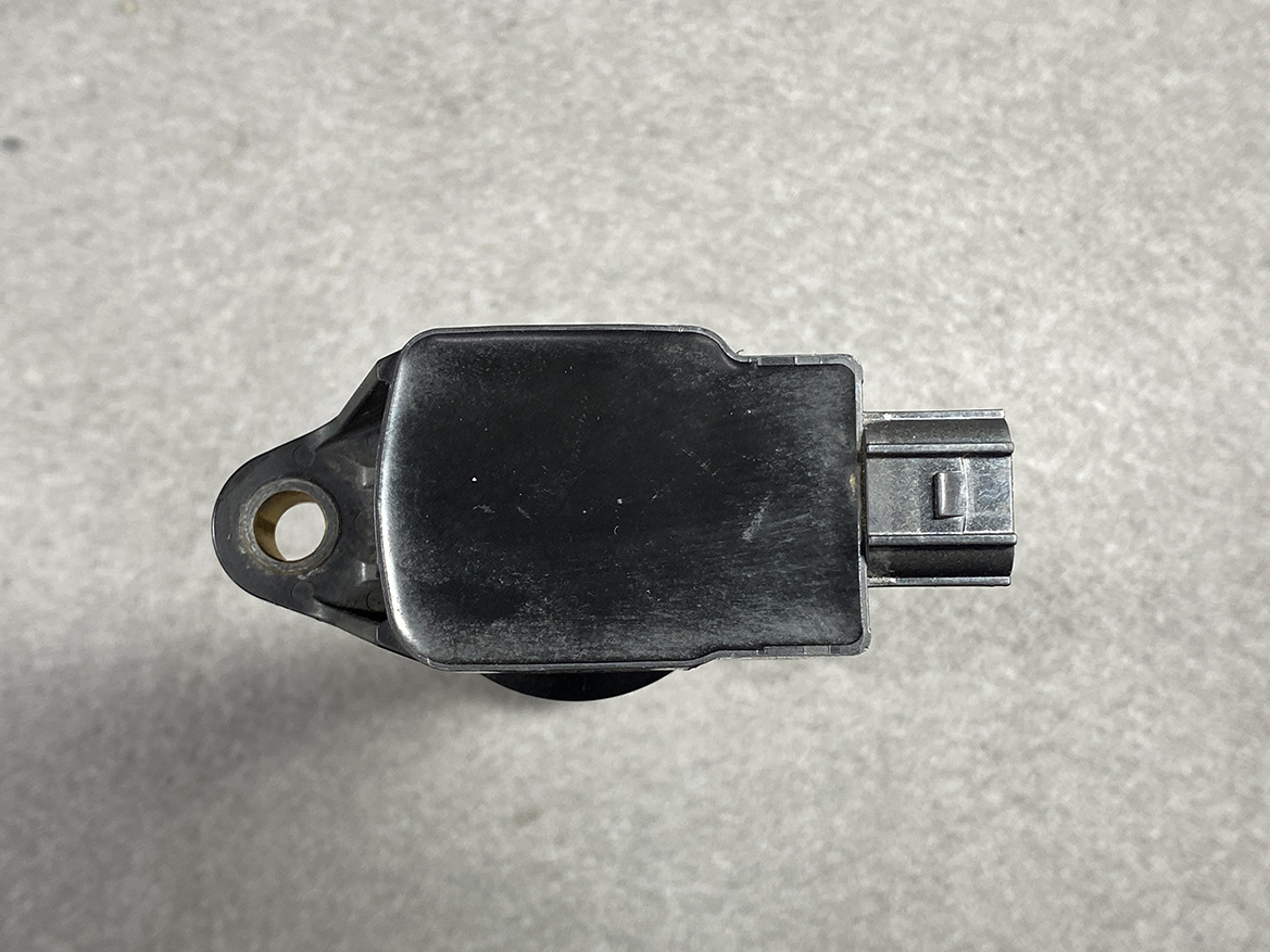 HON-COIL-CM11-119_6 HONDA Genuine IGNITION COIL CM11-119 / L-series Engine » NZ.95 » JDM-PARTS NZ » JDM-PARTS NZ Automotive sensor module with a mounting hole and a two-pin electrical connector against a gray surface. HONDA Genuine IGNITION COIL CM11-119 / L-series Engine » JDM-PARTS NZ
