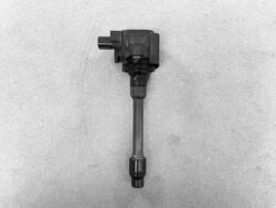 Automotive ignition coil with electrical connector and spark plug boot on a gray background.