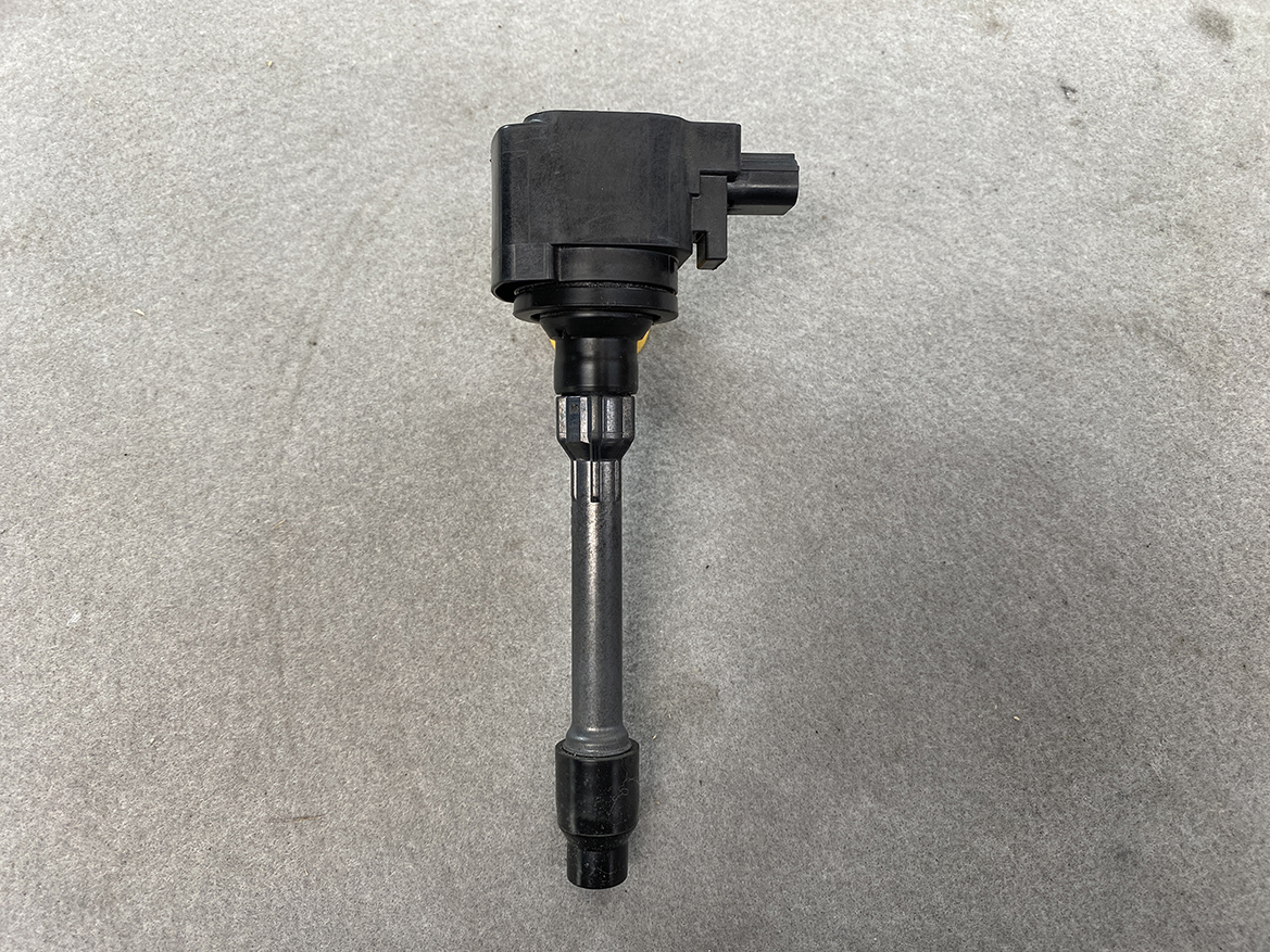 HON-COIL-CM11-121A_4 HONDA Genuine IGNITION COIL CM11-121A / L-series Engine » NZ.95 » JDM-PARTS NZ » JDM-PARTS NZ Automotive ignition coil with electrical connector on top and spark plug boot at bottom, laid on concrete surface HONDA Genuine IGNITION COIL CM11-121A / L-series Engine » JDM-PARTS NZ