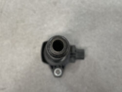 Close-up of a black cylindrical nozzle with a hollow center, viewed from above on a gray surface.