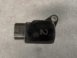 Black automotive diagnostic/plug-in adapter with a left-side connector and a mounting tab with a metal hole on the right.