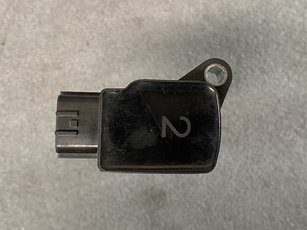 MAZ-COIL-LF2L_6 MAZDA Genuine IGNITION COIL K4238 / LF2L-18-100 / LF, L3 Engine » NZ.95 » JDM-PARTS NZ » JDM-PARTS NZ Black automotive diagnostic/plug-in adapter with a left-side connector and a mounting tab with a metal hole on the right. MAZDA Genuine IGNITION COIL K4238 / LF2L-18-100 / LF, L3 Engine » JDM-PARTS NZ