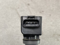 Close-up of a weather-sealed automotive multi-pin connector with five visible gold contacts inside a black plastic housing on a sensor mount.