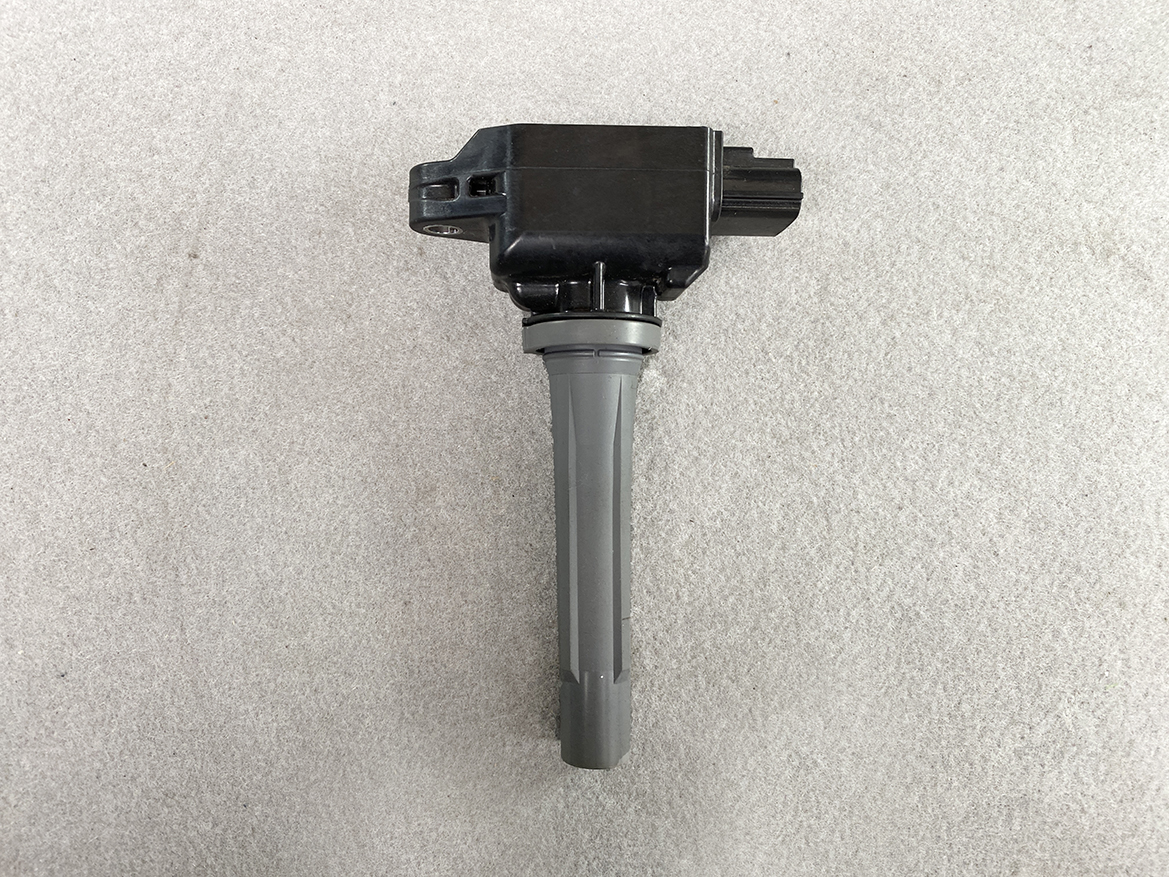 MAZ-COIL-P51R18100_4 MAZDA Genuine IGNITION COIL H6T15571 / P51R-18-100 SKYACTIV-G » NZ.95 » JDM-PARTS NZ » JDM-PARTS NZ Ignition coil pack with a gray boot and electrical connector, photographed on a beige surface. MAZDA Genuine IGNITION COIL H6T15571 / P51R-18-100 SKYACTIV-G » JDM-PARTS NZ
