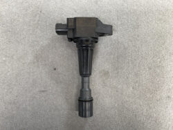 Ignition coil with spark plug boot on a gray surface, used in a car engine