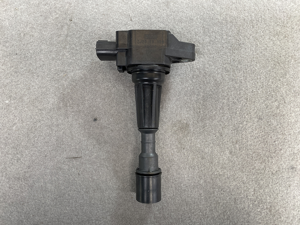 MAZ-COIL-ZJ20_4 MAZDA Genuine IGNITION COIL K5014 / ZJ20-18-100 / Z-series Engine » NZ.95 » JDM-PARTS NZ » JDM-PARTS NZ Ignition coil with spark plug boot on a gray surface, used in a car engine MAZDA Genuine IGNITION COIL K5014 / ZJ20-18-100 / Z-series Engine » JDM-PARTS NZ