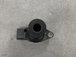 Top view of a black plastic cylindrical component with a hollow center and a mounting flange, likely a sensor or valve part from a vehicle.