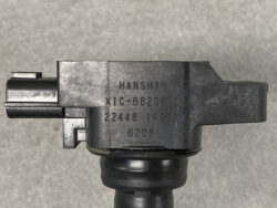 Close-up of a dark pistol component with stamped markings: HANSHIN and other characters on a black metal surface against a gray background.