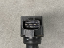 Close-up of a black automotive electrical connector with three exposed metal pins inside.