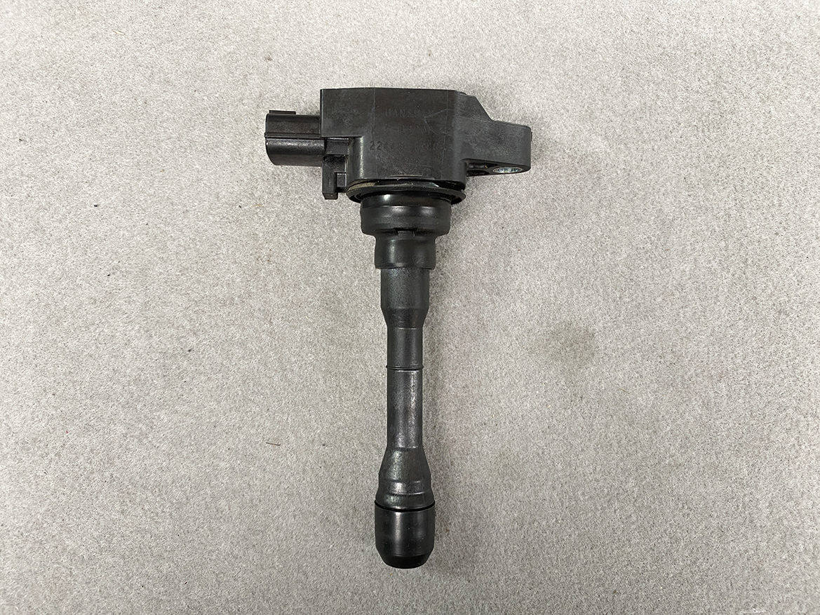 NIS-COIL-1KC0A_4 NISSAN RENAULT Genuine IGNITION COIL 22448 1KC0A / MR, QR Engine » NZ.95 » JDM-PARTS NZ » JDM-PARTS NZ Automotive ignition coil with spark plug boot on a gray surface. NISSAN RENAULT Genuine IGNITION COIL 22448 1KC0A / MR, QR Engine » JDM-PARTS NZ