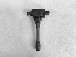 Automotive ignition coil with electrical connector resting on a gray surface