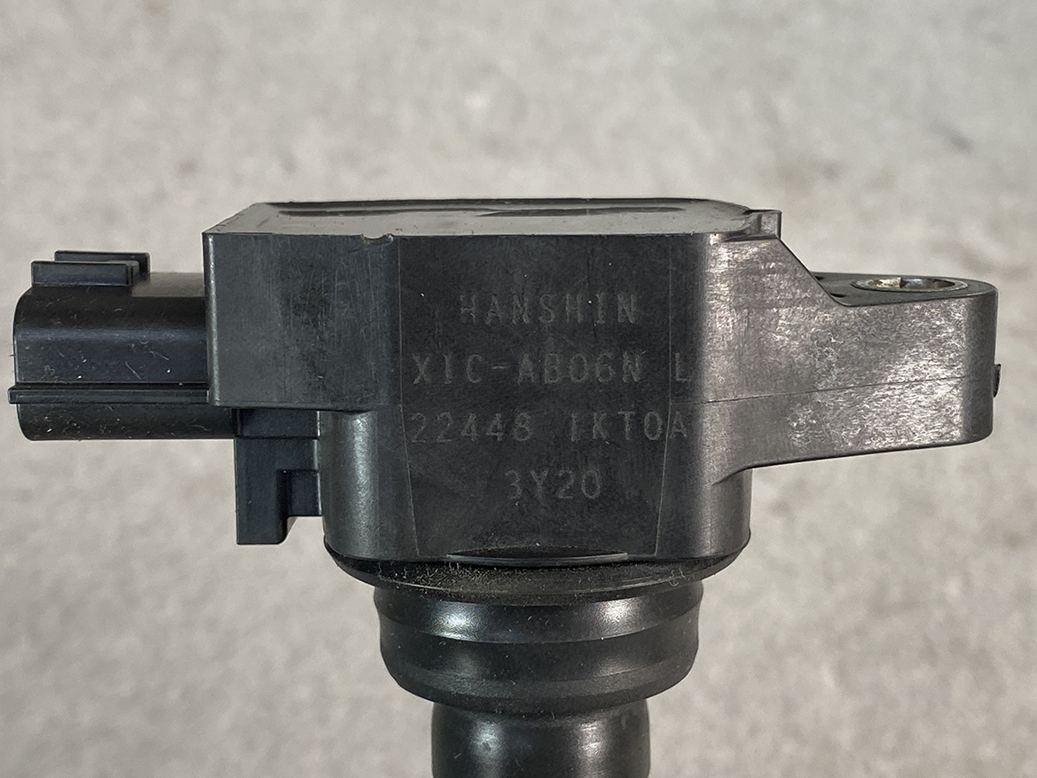 NIS-COIL-1KT0A_2 NISSAN Genuine Ignition Coil 22448 1KT0A / HR, MR, QR Engine » NZ.95 » JDM-PARTS NZ » JDM-PARTS NZ Close-up of a black plastic automotive sensor housing mounted on a shaft, with engraved serial numbers visible on the side. NISSAN Genuine Ignition Coil 22448 1KT0A / HR, MR, QR Engine » JDM-PARTS NZ