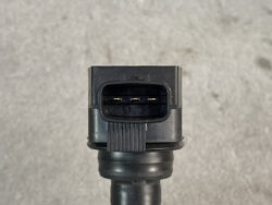 Close-up of a black three-pin automotive electrical connector with gold pins on a cable.
