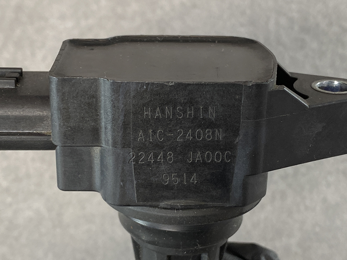 NIS-COIL-JA00C_2 NISSAN Genuine IGNITION COIL 22448 JA00C / MR QR Engine » NZ.95 » JDM-PARTS NZ » JDM-PARTS NZ Close-up of a black mounting component labeled HANSHIN ANC-2408N with serial numbers etched on the side NISSAN Genuine IGNITION COIL 22448 JA00C / MR QR Engine » JDM-PARTS NZ