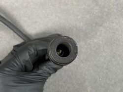 Small rubber seal or plug with a hollow center, held by a gloved hand.
