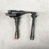 Pair of automotive ignition coil packs with spark plug boots laid on a concrete floor
