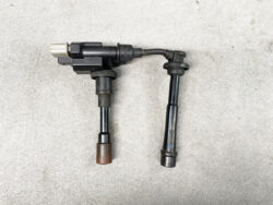 Pair of automotive ignition coil packs with spark plug boots laid on a concrete floor