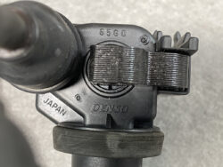 Close-up of a black DENSO automotive component with a textured strap and embossed JAPAN and DENSO markings.
