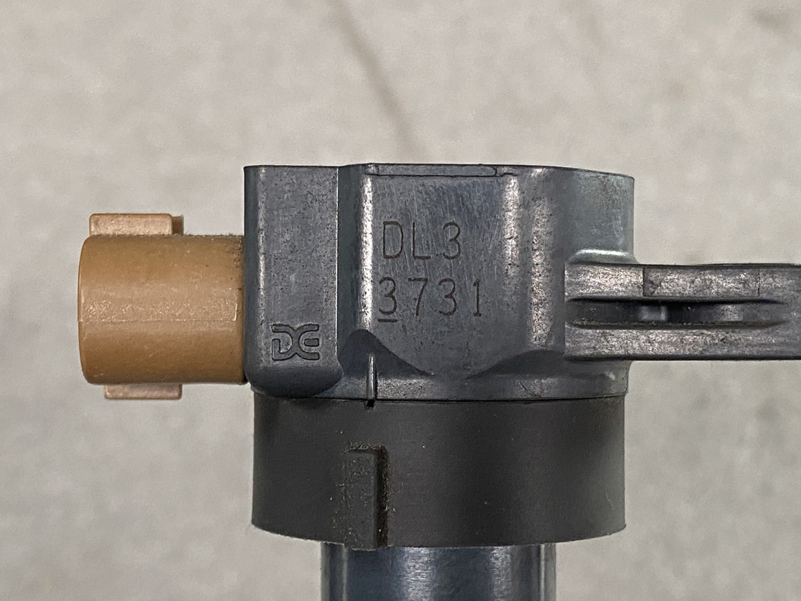 SUZ-COIL-DL3_2 SUZUKI Genuine IGNITION COIL / DL3 / 3731 / K12B, K6A, R06A Engine » NZ.95 » JDM-PARTS NZ » JDM-PARTS NZ Close-up of a metal valve component with an orange plastic cap and a long lever, stamped DL3 3731. SUZUKI Genuine IGNITION COIL / DL3 / 3731 / K12B, K6A, R06A Engine » JDM-PARTS NZ
