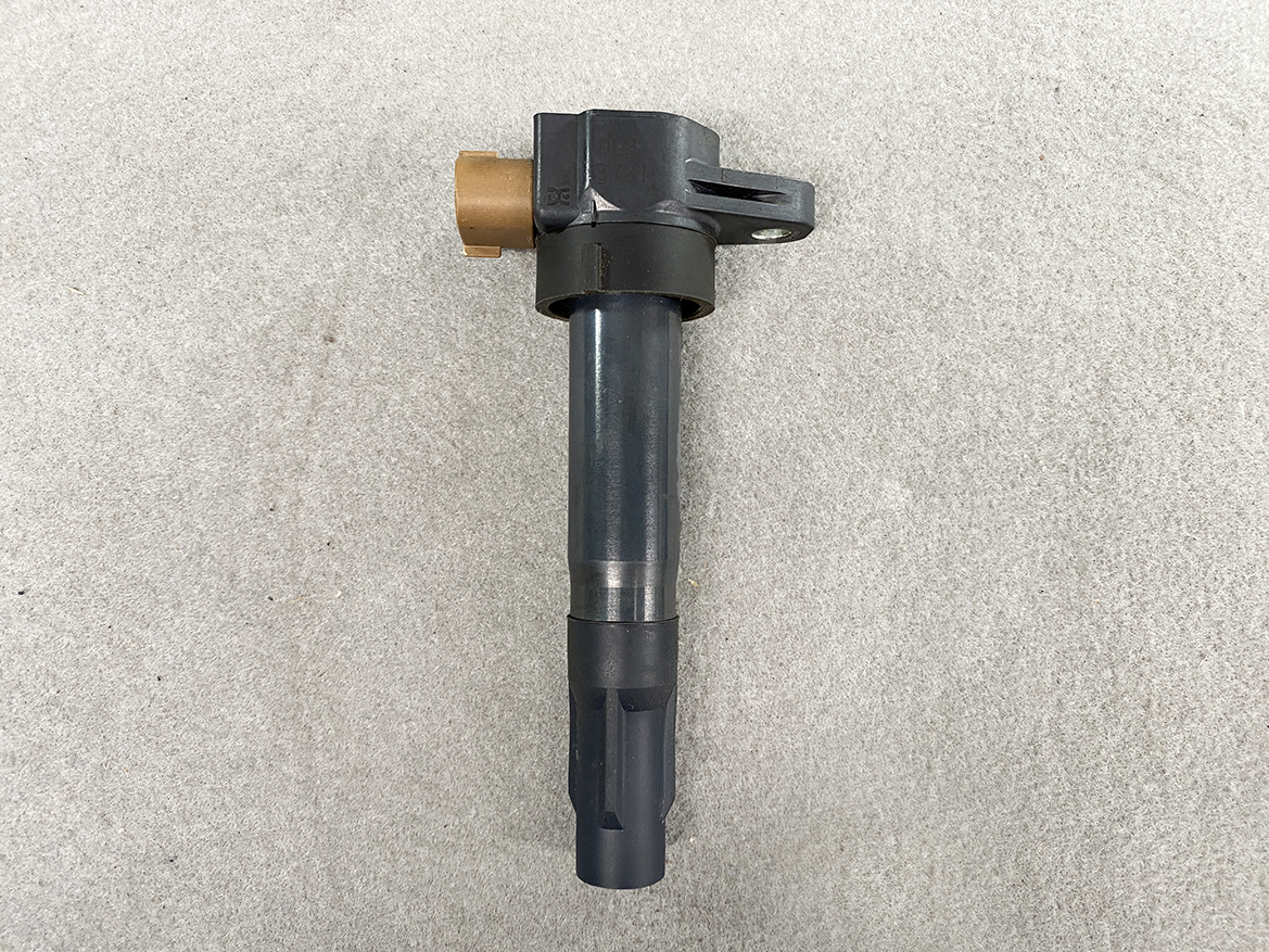 SUZ-COIL-DL3_4 SUZUKI Genuine IGNITION COIL / DL3 / 3731 / K12B, K6A, R06A Engine » NZ.95 » JDM-PARTS NZ » JDM-PARTS NZ Automotive fuel injector with a brown electrical connector and mounting tab, lying on a concrete surface. SUZUKI Genuine IGNITION COIL / DL3 / 3731 / K12B, K6A, R06A Engine » JDM-PARTS NZ