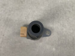 Top-down view of a small gray plastic automotive sensor with a circular hollow opening and a side brown electrical connector, mounted on a metal surface.
