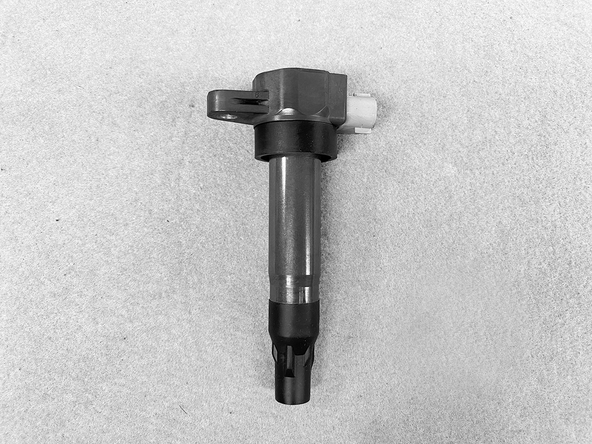 SUZ-COIL-DL4_1 SUZUKI Genuine IGNITION COIL / DL4 / 5309 / R06A Engine » NZ.95 » JDM-PARTS NZ » JDM-PARTS NZ Automotive fuel injector lying on a gray surface, showing metal body and plastic nozzle at the bottom. SUZUKI Genuine IGNITION COIL / DL4 / 5309 / R06A Engine » JDM-PARTS NZ