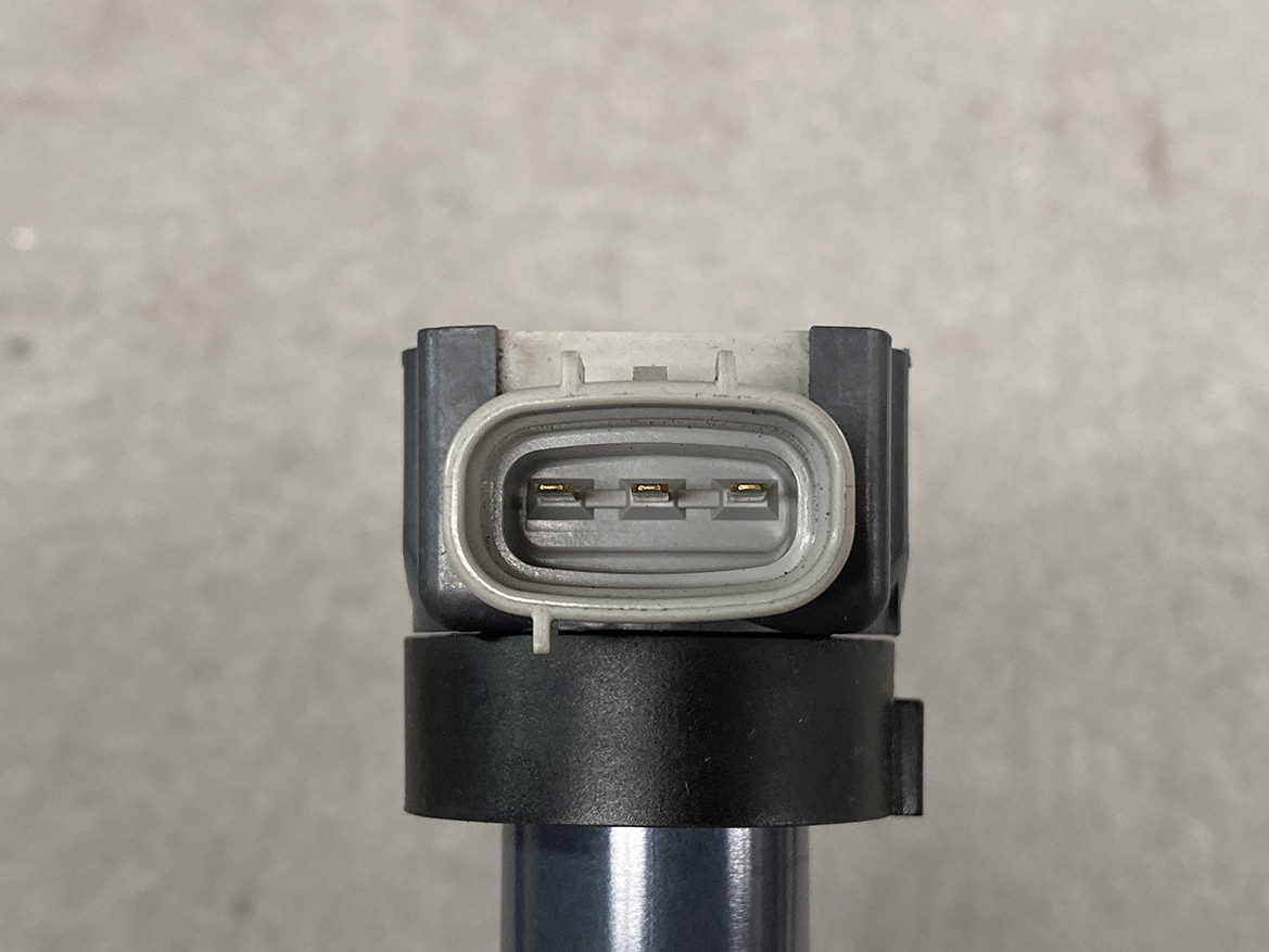 SUZ-COIL-DL4_3 SUZUKI Genuine IGNITION COIL / DL4 / 5309 / R06A Engine » NZ.95 » JDM-PARTS NZ » JDM-PARTS NZ Close-up of a gray oval automotive electrical connector with three gold pins inside. SUZUKI Genuine IGNITION COIL / DL4 / 5309 / R06A Engine » JDM-PARTS NZ
