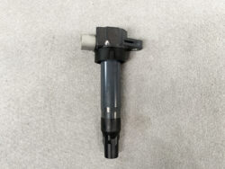 Automotive ignition coil with a grey metal body and black plastic top, including a mounting tab and electrical connector