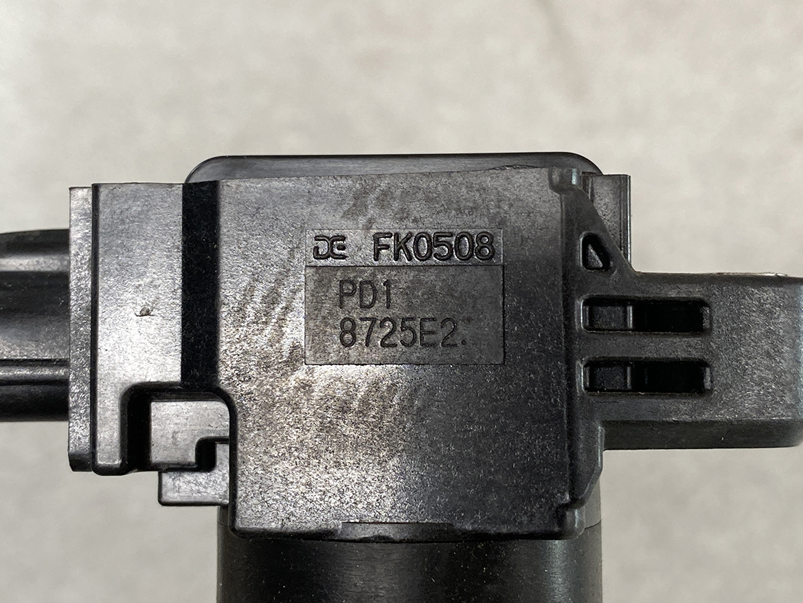 SUZ-COIL-FK0508_2 SUZUKI Genuine IGNITION COIL FK0508 / R06A, K12B Engine » NZ.95 » JDM-PARTS NZ » JDM-PARTS NZ Close-up of a black plastic connector housing with engraved part numbers FK0508 and PD1 8725E2 on the surface SUZUKI Genuine IGNITION COIL FK0508 / R06A, K12B Engine » JDM-PARTS NZ
