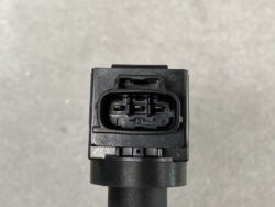 Close-up of a black, three-pin automotive electrical connector with visible gold contacts on a gray background edge of a cable starter.