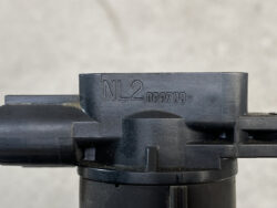 Close-up of a black firearm component with the engraving NL.2 099700- on the metal surface, shown from the side.