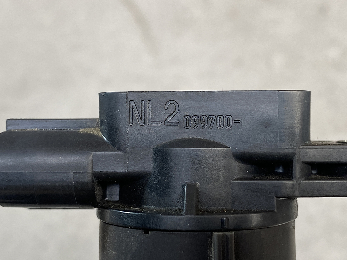 SUZ-COIL-NL2_2 SUZUKI Genuine IGNITION COIL DENSO NL2 099700 / R06A, K6A Engine » NZ.95 » JDM-PARTS NZ » JDM-PARTS NZ Close-up of a black firearm component with the engraving NL.2 099700- on the metal surface, shown from the side. SUZUKI Genuine IGNITION COIL DENSO NL2 099700 / R06A, K6A Engine » JDM-PARTS NZ