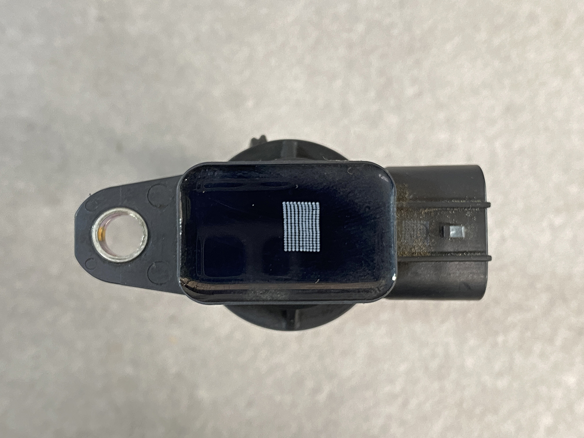 SUZ-COIL-NL2_7 SUZUKI Genuine IGNITION COIL DENSO NL2 099700 / R06A, K6A Engine » NZ.95 » JDM-PARTS NZ » JDM-PARTS NZ Black rectangular sensor module mounted on a circular base, with a metal mounting hole on the left and a small grid of contacts on top viewed from above. SUZUKI Genuine IGNITION COIL DENSO NL2 099700 / R06A, K6A Engine » JDM-PARTS NZ