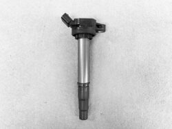 Spark plug for an internal combustion engine photographed against a gray background, showing the metal shell and ceramic tip at the bottom.