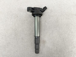 Car ignition coil with electrical connector at the top and a cylindrical metal body, used to spark the engine's cylinders at ignition time.