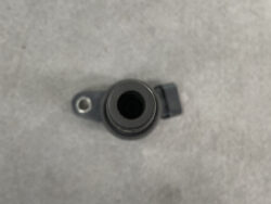 Close-up of a small black circular camera lens or sensor housing on a gray surface, with a metal mounting tab to the left.