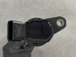 Automotive crankshaft/engine position sensor with mounting tab and electrical connector.