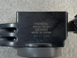 Close-up of a black Toyota automotive component with DENSO branding and model/part numbers (90919-02281) and Made in Japan marking on the housing.