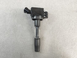 Ignition coil with spark plug boot and electrical connector on a gray background (auto part).