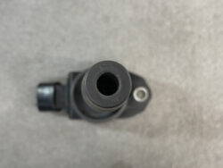 Close-up, top-down view of a black plastic connector or nozzle with a central hollow opening on a gray background
