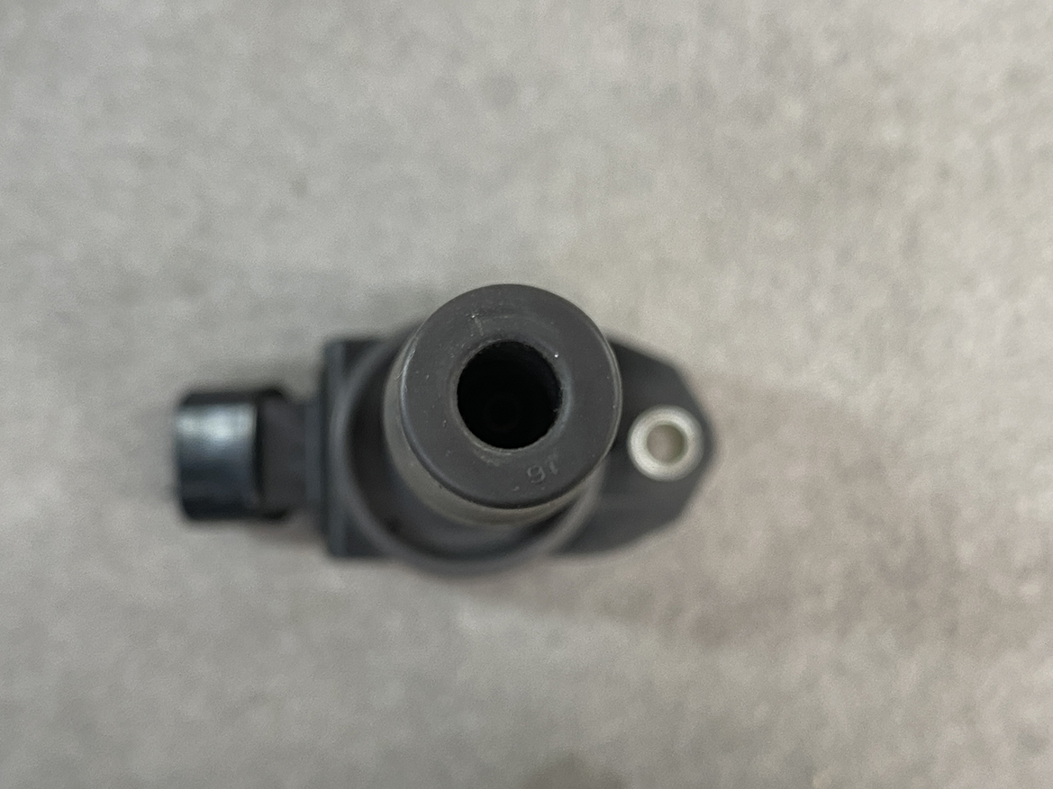 TOY-COIL-02281_5 TOYOTA / DAIHATSU Genuine IGNITION COIL 90919-02281 / NR, KR Engine » NZ.95 » JDM-PARTS NZ » JDM-PARTS NZ Close-up, top-down view of a black plastic connector or nozzle with a central hollow opening on a gray background TOYOTA / DAIHATSU Genuine IGNITION COIL 90919-02281 / NR, KR Engine » JDM-PARTS NZ