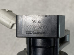 Close-up of a gray metal component stamped with 0614, 19500-B2050, and DE Diamond.