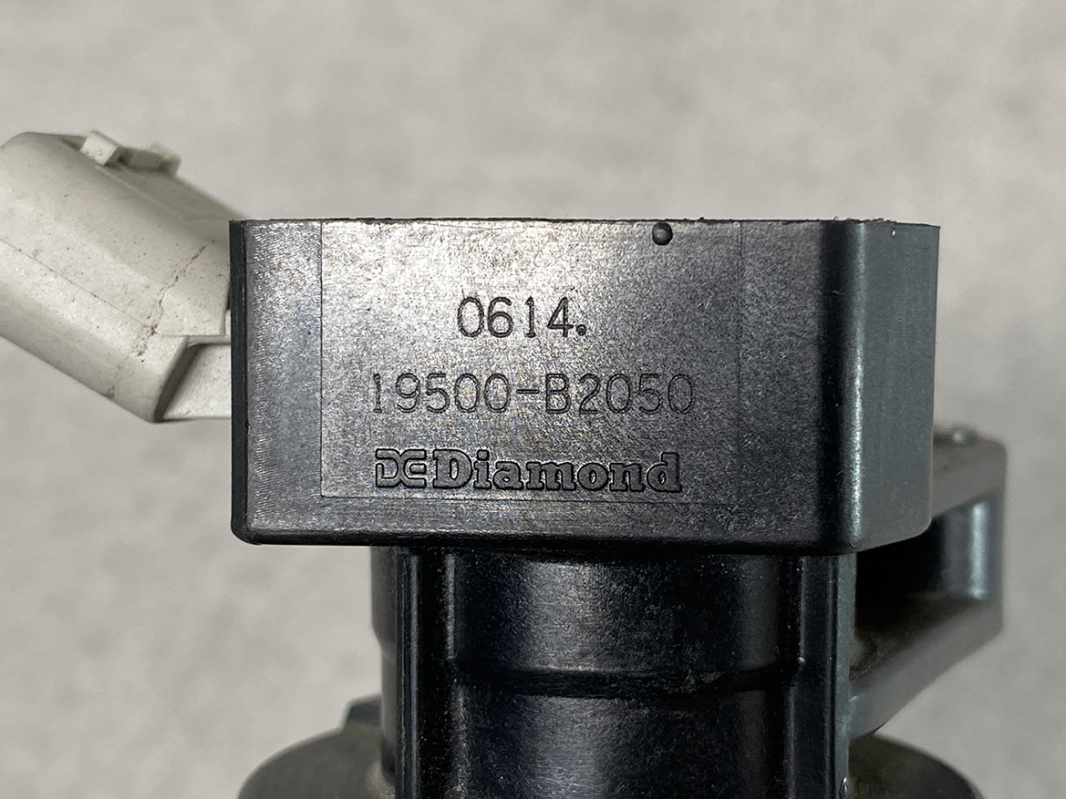 TOY-COIL-B2050_2 TOYOTA / DAIHATSU Genuine IGNITION COIL / 19500-B2050 / KF Engine » NZ.95 » JDM-PARTS NZ » JDM-PARTS NZ Close-up of a gray metal component stamped with 0614, 19500-B2050, and DE Diamond. TOYOTA / DAIHATSU Genuine IGNITION COIL / 19500-B2050 / KF Engine » JDM-PARTS NZ