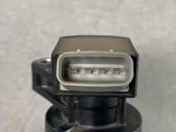 Close-up of a rectangular gray automotive electrical connector with five gold pins inside on a black housing.